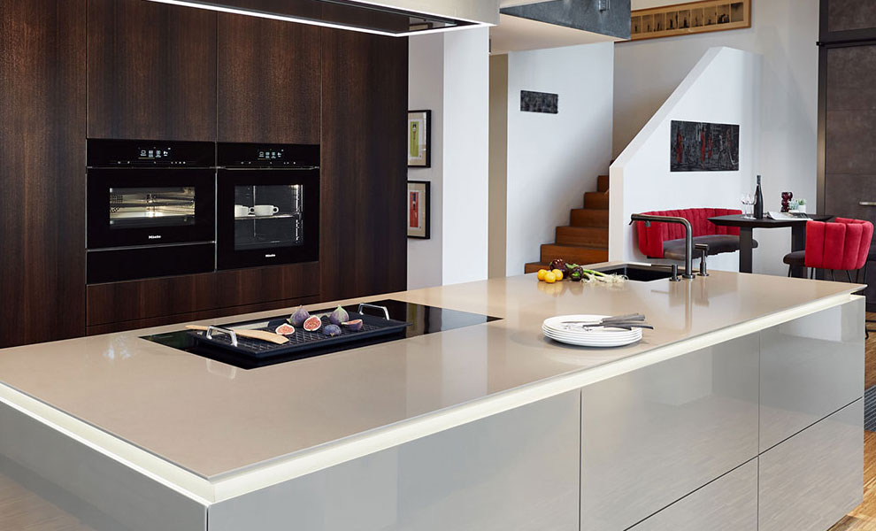 Dunkle Naturholz Schränke mit Küchengeräten und eine helle Kücheninsel mit Beige Arbeitsplatte  Dunkle Naturholz Schränke mit Küchengeräten und eine helle Kücheninsel mit Beige Arbeitsplatte