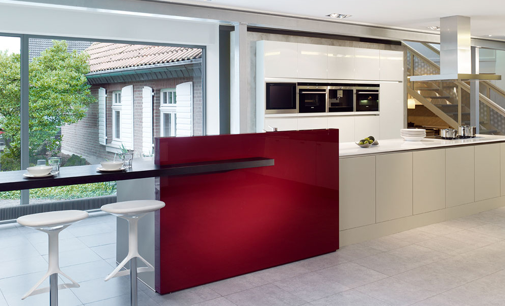 Lange Beige Kücheninsel mit Weißer Arbeitsfläche und schwarzer Theke, gegenüber liegen schwebende Schränke mit Küchengeräten  Lange Beige Kücheninsel mit Weißer Arbeitsfläche und schwarzer Theke, gegenüber liegen schwebende Schränke mit Küchengeräten