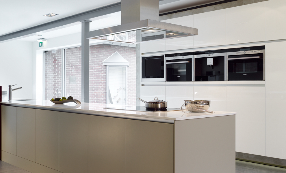 Lange Beige Kücheninsel mit Weißer Arbeitsfläche und schwarzer Theke, gegenüber liegen schwebende Schränke mit Küchengeräten 
 Lange Beige Kücheninsel mit Weißer Arbeitsfläche und schwarzer Theke, gegenüber liegen schwebende Schränke mit Küchengeräten