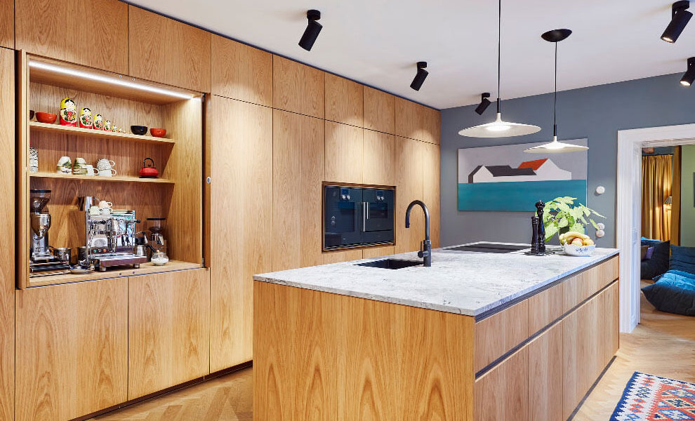 Helle Küche aus Naturholz und Arbeit Fläche aus Granit mit Kücheninsel und Schränken. 