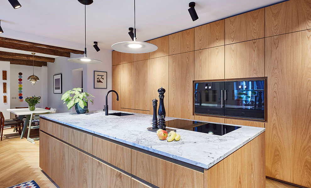 Helle Küche aus Naturholz und Arbeitsfläche aus Granit mit Kücheninsel und Schränken.