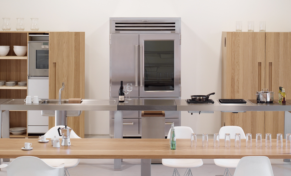 Offene Küche aus Metall Tischen mit Küchengeräten und Naturholz Schränken 