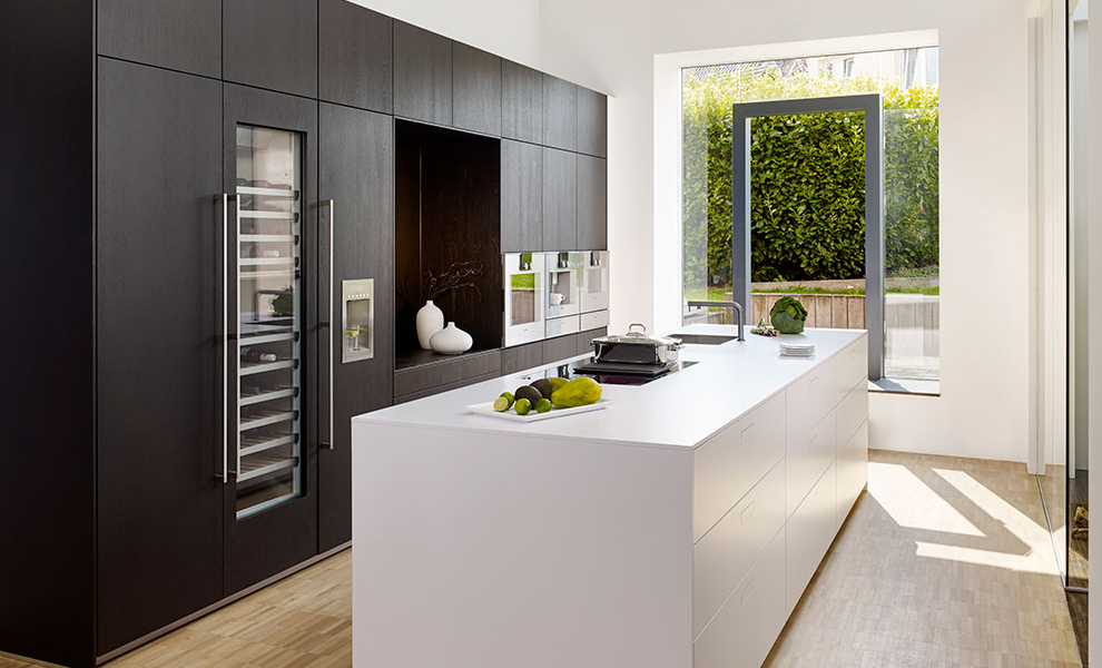 Schwarze Küchenwand mit Küchengeräten und Weißer Kücheninsel mit Arbeitsfläche Schwarze Küchenwand mit Küchengeräten und Weißer Kücheninsel mit Arbeitsfläche