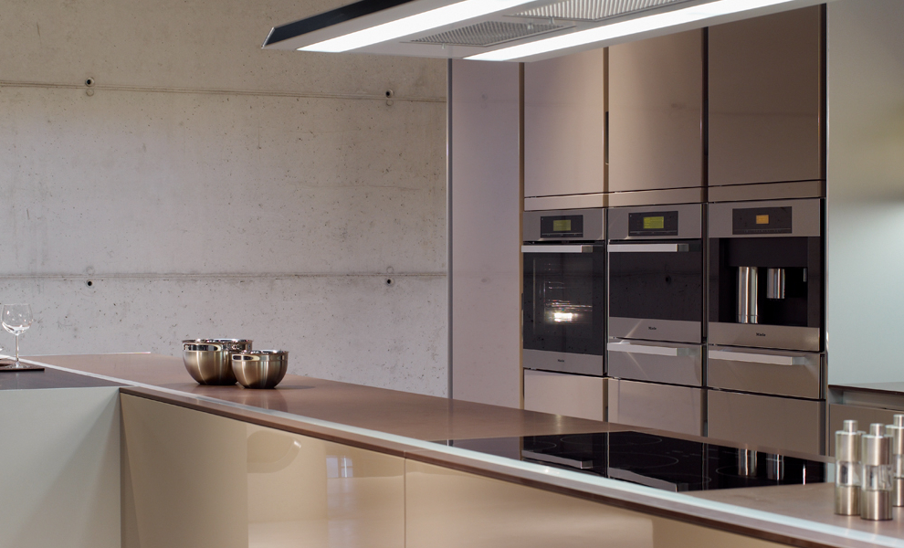 Große Beige Küche mit Länglicher Kücheninsel und Theke. Gegenüber ist eine Arbeitsfläche mit Hängeschränken und Küchengeräten Große Beige Küche mit Länglicher Kücheninsel und Theke. Gegenüber ist eine Arbeitsfläche mit Hängeschränken und Küchengeräten