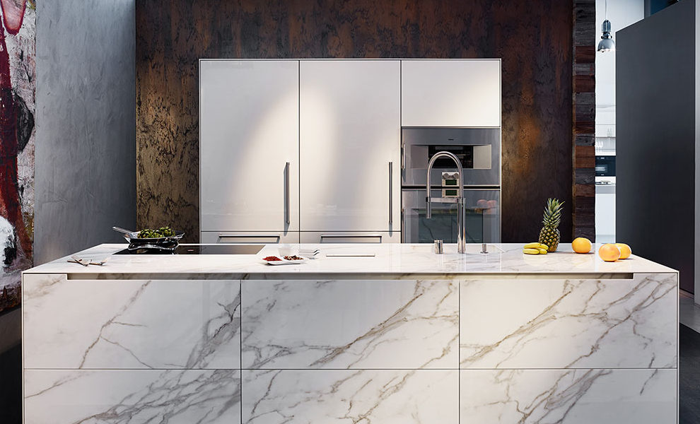 Kücheninsel aus Hellen Granit mit Spüle und Herd. Weiße Wandwandschränke mit Küchengeräten Kücheninsel aus Hellen Granit mit Spüle und Herd. Weiße Wandwandschränke mit Küchengeräten