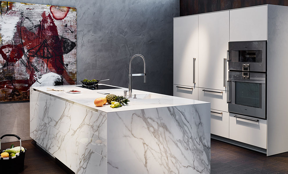 Kücheninsel aus Hellen Granit mit Spüle und Herd. Weiße Wandwandschränke mit Küchengeräten Kücheninsel aus Hellen Granit mit Spüle und Herd. Weiße Wandwandschränke mit Küchengeräten