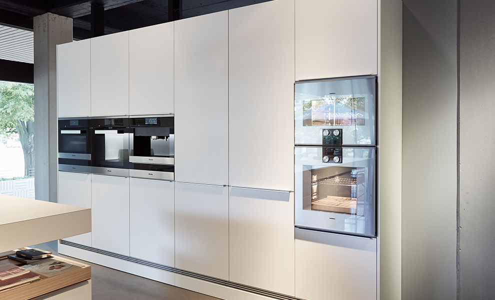 Weiße Schrankzeile mit integrierten Küchengeräten Weiße Schrankzeile mit integrierten Küchengeräten